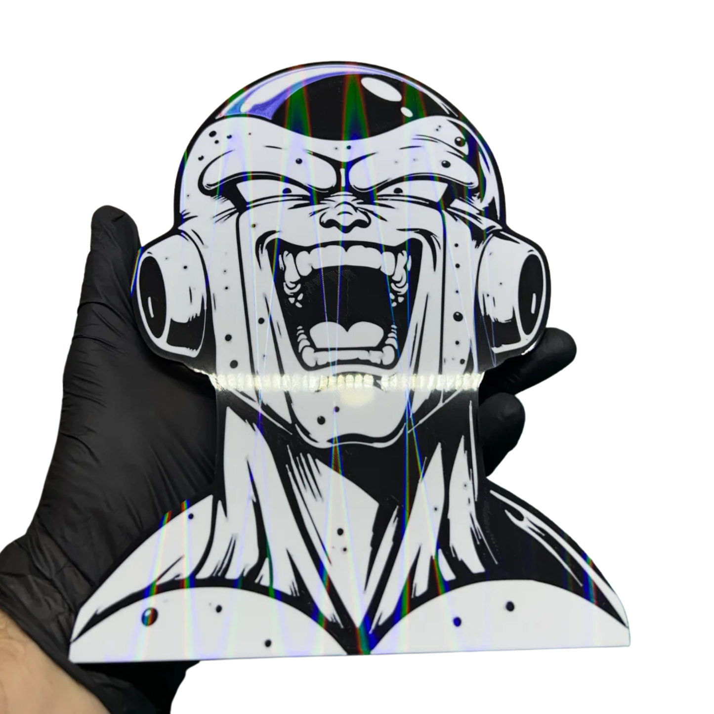 Aplique decorativo de Freezer de Dragon Ball Z en blanco y negro, mostrando intensos reflejos holográficos de colores iridiscentes, sostenido por una mano.