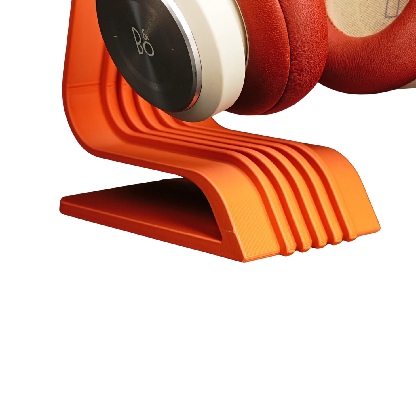 Primer plano de la base y la parte inferior del porta audífonos de diseño curvo color naranja, mostrando sus líneas estriadas y la parte donde descansa el auricular.