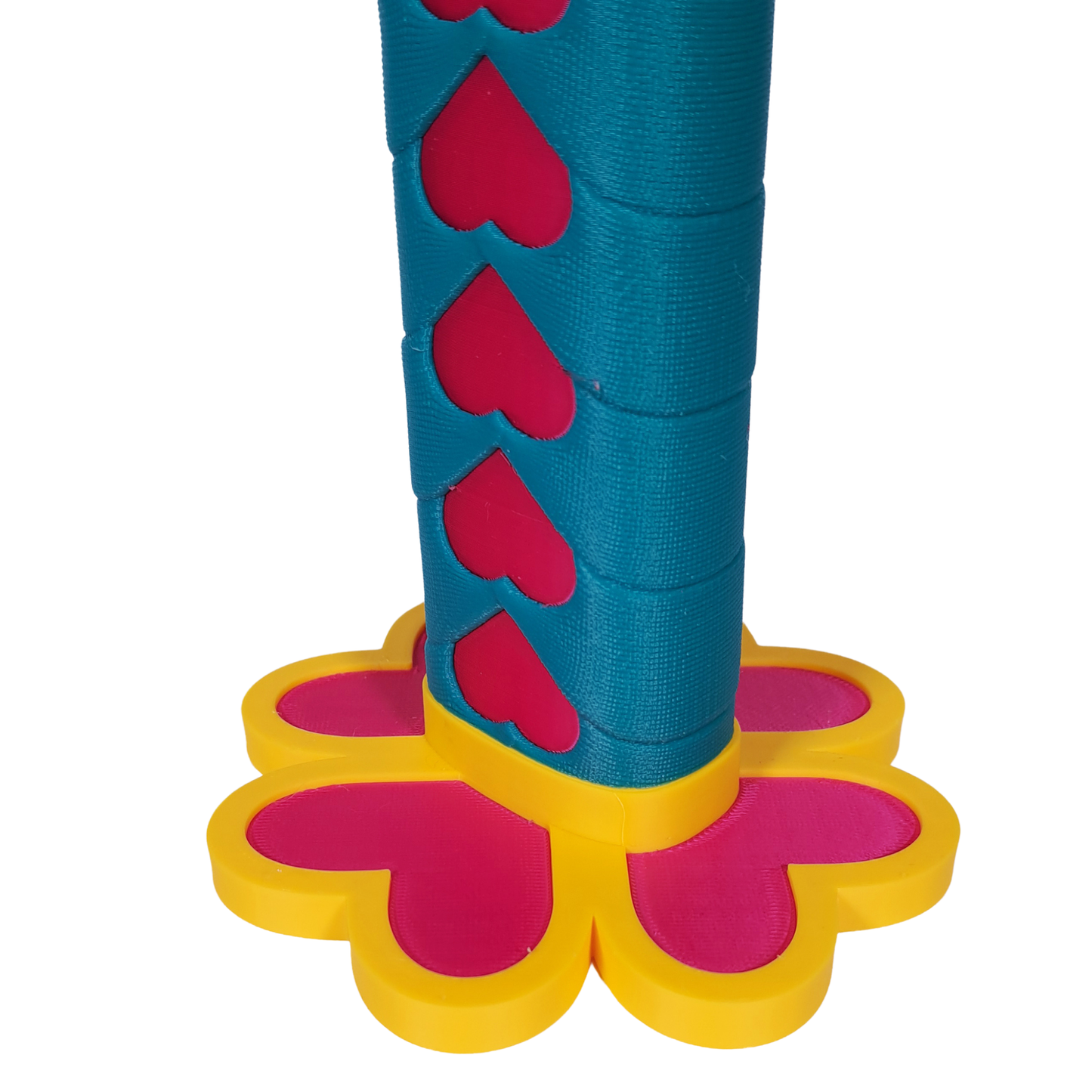 Primer plano de la base y la guarda (tsuba) de la katana retráctil de Mitsuri Kanroji, mostrando los detalles de los corazones en la guarda amarilla y el mango con patrón de corazones rosas sobre azul-verdoso.