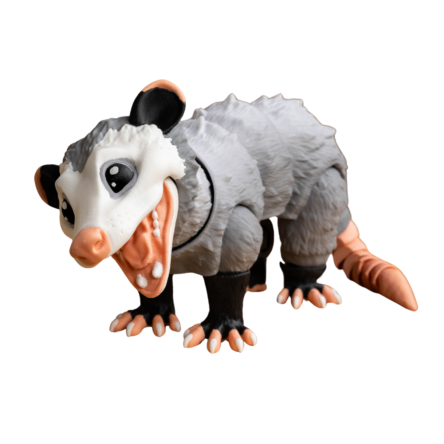 Figura articulada de zarigüeya en color gris, con boca abierta y expresión defensiva o asustada, mostrando sus dientes y lengua.