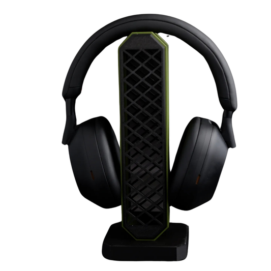 Porta audífonos gaming vertical en color negro con detalles verdes y patrón de rejilla, sosteniendo unos auriculares gaming negros.
