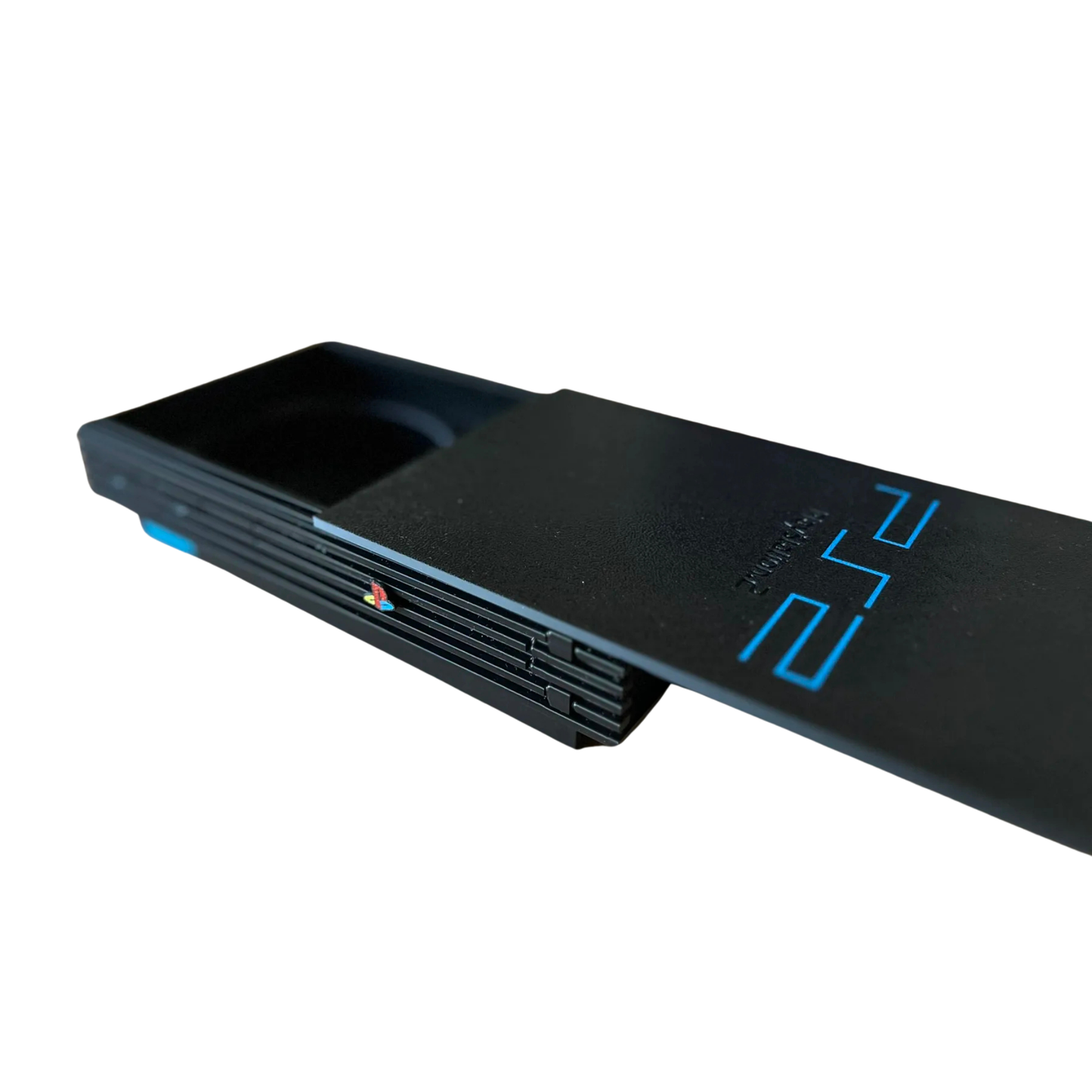 Vista lateral de la réplica de la consola PlayStation 2 Slim negra, con la bandeja de los posavasos ligeramente abierta, mostrando el mecanismo deslizable.