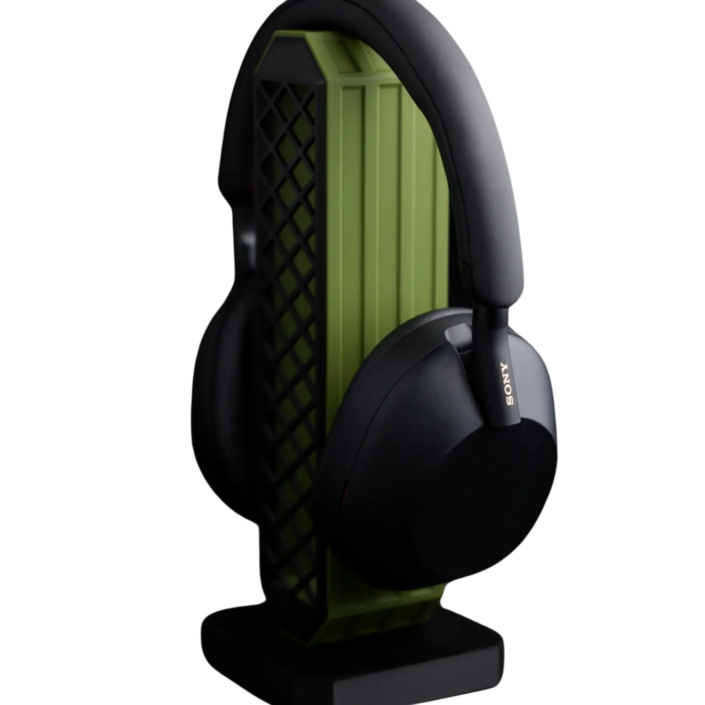 Soporte lateral para headset gaming con diseño rectangular en negro y verde, con unos audífonos negros colgados en la parte superior.