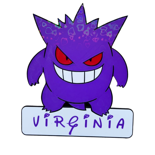 Aplique decorativo de Gengar Pokémon de color morado, con ojos rojos y sonrisa, sobre una placa blanca con el nombre "VIRGINIA" y un sutil patrón de corazones.