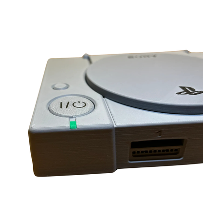 Primer plano del botón de encendido y el indicador de luz verde en la réplica en miniatura de la consola PlayStation 1.