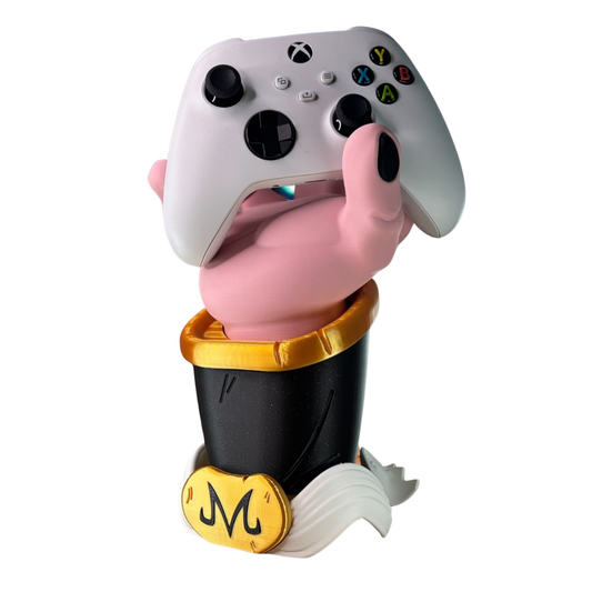 Porta mando con la mano rosada de Majin Buu de Dragon Ball Z, emergiendo de su pantalón negro con el símbolo "M", sosteniendo un control de Xbox blanco.