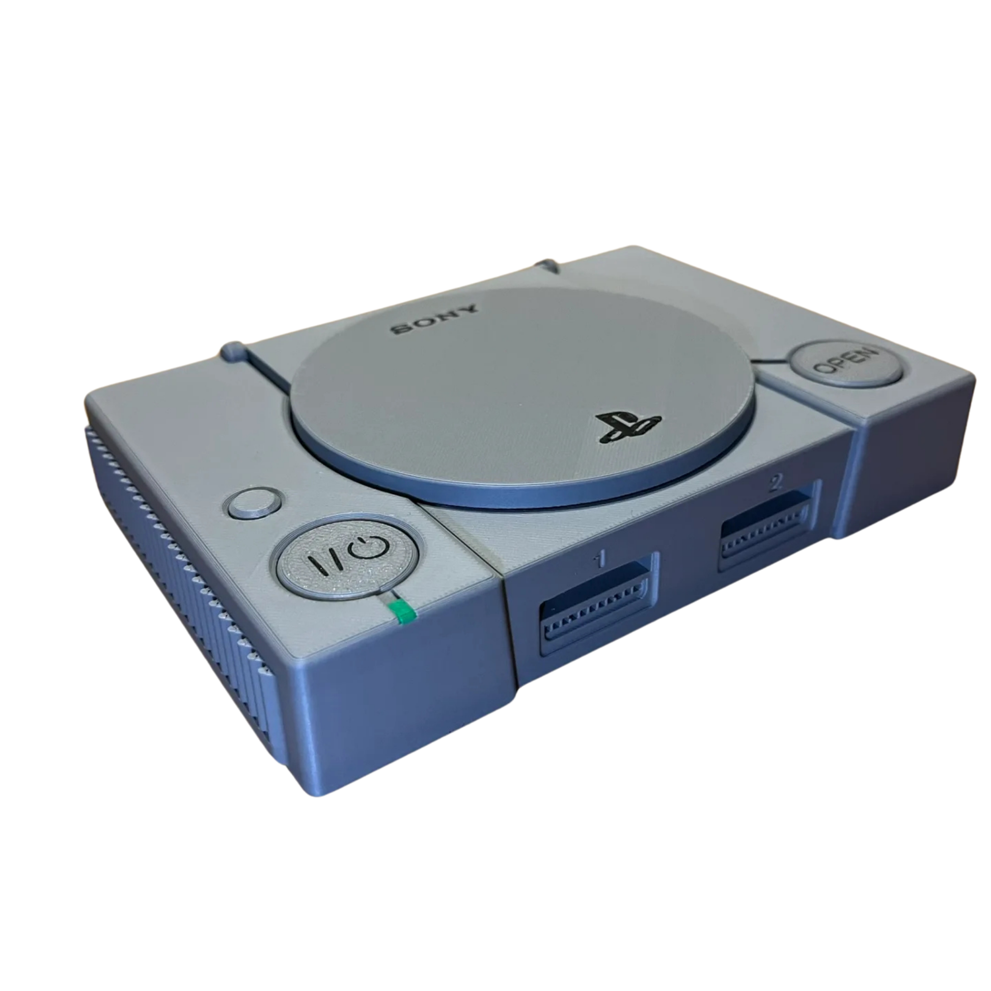 Vista delantera de la réplica de la consola PlayStation 1 gris, mostrando los puertos de control y el botón de encendido, con la tapa abierta.