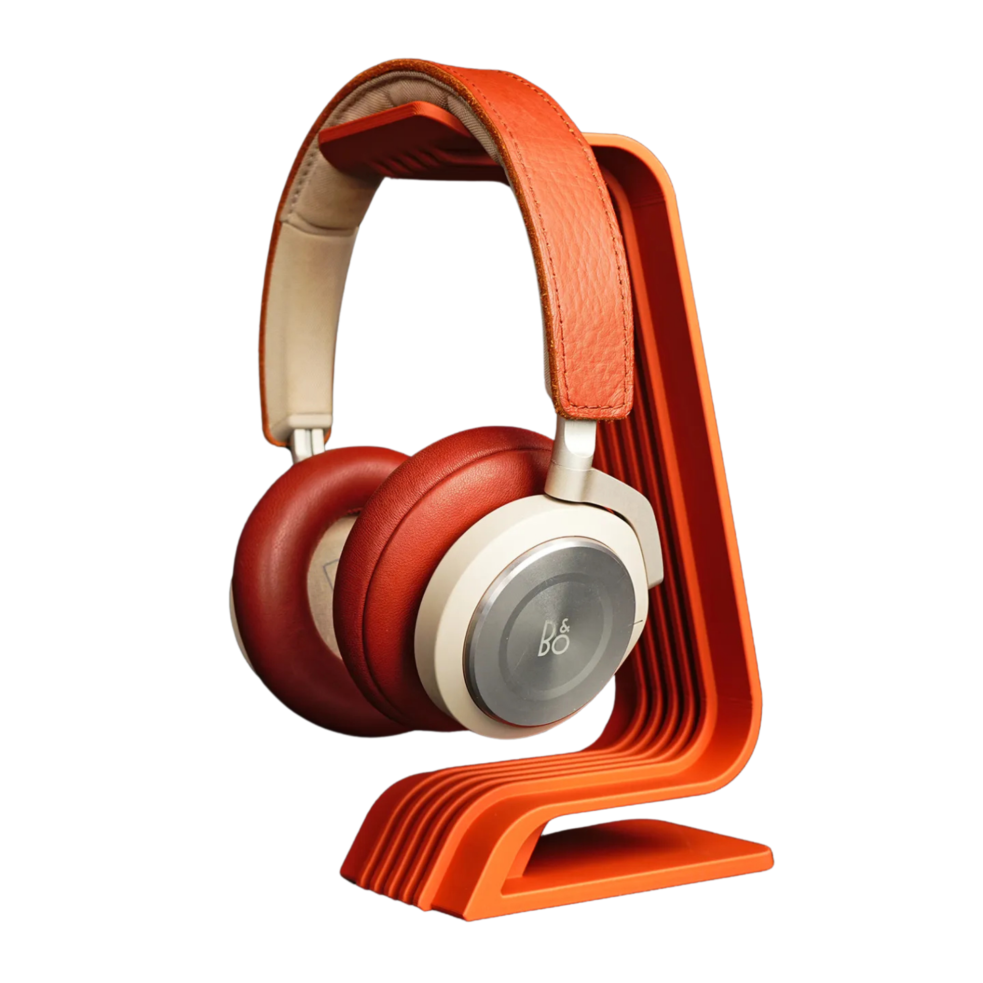 Soporte para audífonos de diseño curvo en color naranja, con auriculares rojos y crema colgados, mostrando el ángulo ergonómico de apoyo.