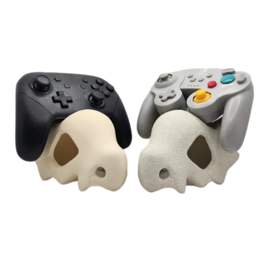 Par de soportes para mandos con diseño de calavera de Cubone (Pokémon), uno con mando Switch Pro negro y otro con mando estilo GameCube gris, mostrando diferentes acabados.