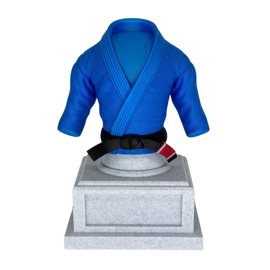 Trofeo de Gi de Jiu-Jitsu en color azul con cinturón negro y barra roja, montado sobre una base de trofeo gris, visto de frente.